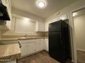 Well-organized kitchen with white cabinets, black appliances, and dark wood flooring at 3810 W Belmont Ave, Phoenix, AZ 85051