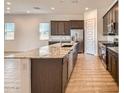 Kitchen features an island, granite countertops, stainless steel appliances, and wood-look tile floors at 15032 W Gray Fox Trl, Surprise, AZ 85387