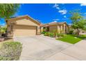 Exterior view of a desert home with a spacious driveway and lush landscaping at 15576 W Yucatan Dr, Surprise, AZ 85379