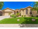 Charming single-story home with desert landscaping, artificial grass, and a two-car garage at 15576 W Yucatan Dr, Surprise, AZ 85379