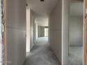 Long hallway showing unfinished drywall and concrete floors, offering a glimpse into the home's layout at 15768 W Beryl Ave, Waddell, AZ 85355