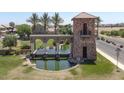 Elegant community entrance with a water feature, stone tower, and lush landscaping at 36503 W San Ildefanso Ave, Maricopa, AZ 85138