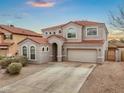 A charming two-story home with a red tile roof, stucco exterior, arched windows, desert landscaping and an attached two-car garage at 647 E Palomino Way, San Tan Valley, AZ 85143