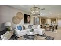 Bright living room features a large white couch, stylish decor, and an open concept design leading to the kitchen at 1333 S 239Th Dr, Buckeye, AZ 85326