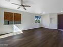 Spacious living room featuring wood floors, a ceiling fan, and windows to the front yard at 1131 E Catino St, San Tan Valley, AZ 85140