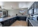 Functional kitchen with dark cabinets, granite counters, tile flooring, and natural light at 13547 W Peck Dr, Litchfield Park, AZ 85340