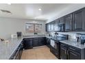 Functional kitchen features dark cabinets, tile flooring, granite countertops, and a window at 13547 W Peck Dr, Litchfield Park, AZ 85340