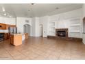 Open-concept living space featuring a stone fireplace, kitchen island, and tile floors at 14994 W Charter Oak Rd, Surprise, AZ 85379