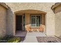 Inviting front porch with seating, decorative plants, and an arched entryway at 25742 N 103Rd Dr, Peoria, AZ 85383