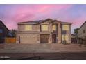 Two-story home featuring a driveway, a two-car garage, and solar panels on the roof at sunset at 3124 W Redbird Rd, Phoenix, AZ 85083