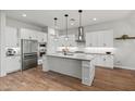 The bright kitchen features stainless appliances, a kitchen island, light countertops, and wood-look flooring at 11241 N Blakely St, Surprise, AZ 85388