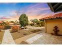 Home exterior showing a stone tile driveway, desert landscaping, and a mature shade tree at 12448 N 76Th St, Scottsdale, AZ 85260