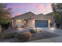Inviting single-story home featuring neutral stucco, a two-car garage, desert landscaping, and an American flag at 2009 E Lindrick Dr, Gilbert, AZ 85298