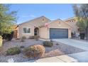 Charming single-story home featuring neutral stucco, a two-car garage, desert landscaping, and an American flag at 2009 E Lindrick Dr, Gilbert, AZ 85298