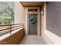 Private balcony featuring a secure entry door with decorative wreath, metal railing, and exterior lighting at 20100 N 78Th Pl # 2210, Scottsdale, AZ 85255