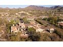An aerial view showing the estate's extensive tile roof, tennis court, and surrounding desert landscape at 23779 N 91St St, Scottsdale, AZ 85255