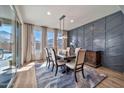 Modern dining room with a wood table, upholstered chairs, a contemporary light fixture, and large windows at 25945 W Sands Dr, Buckeye, AZ 85396