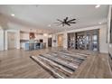 Open-concept living room with wood floors, ceiling fan, a large bookcase and an adjacent kitchen at 25945 W Sands Dr, Buckeye, AZ 85396