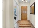 Inviting entryway with tile flooring, a wooden front door, and view into the adjacent bedroom at 42823 N Courage Trl, Anthem, AZ 85086