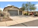 Charming home with a neutral color palette, three-car garage, a long driveway, and desert landscaping at 42823 N Courage Trl, Anthem, AZ 85086