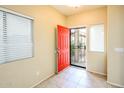 Bright entryway features tile flooring, a red front door, and natural light streaming through the windows at 45049 W Cypress Ln, Maricopa, AZ 85139