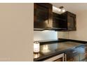 Modern bar area with dark cabinets, glass displays, and sleek black countertop at 4808 N 24Th St # 908, Phoenix, AZ 85016