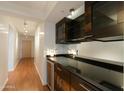 Hallway featuring hardwood floors adjacent to a bar with dark cabinets and black countertop at 4808 N 24Th St # 908, Phoenix, AZ 85016
