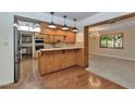 Open-concept kitchen featuring wood cabinetry, eat-in bar, and seamless connection to the dining area at 576 W Moon Valley Dr, Phoenix, AZ 85023