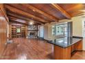 Cozy living room with wood floors, beamed ceilings, a stone fireplace, and a built-in bookshelf at 576 W Moon Valley Dr, Phoenix, AZ 85023
