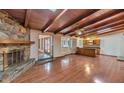 Inviting living room featuring wood beamed ceilings, hardwood floors, and a striking stone fireplace at 576 W Moon Valley Dr, Phoenix, AZ 85023