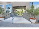 Welcoming building entrance with steps, potted flowers, and glass doors reflecting palm trees at 1 E Lexington Ave # 503, Phoenix, AZ 85012