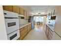 Traditional kitchen with wood cabinets, stainless steel appliances, and a dining area with abundant natural light at 10450 W Sutters Gold Ln, Sun City, AZ 85351