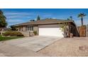 Spacious concrete driveway leading to a two-car garage, complemented by low-maintenance desert landscaping and a clear blue sky at 1506 E Gemini Dr, Tempe, AZ 85283