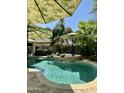 Lush backyard oasis featuring a beautiful pool with sun umbrellas and a stone accent at 15266 N 146Th Ln, Surprise, AZ 85379