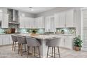 Bright kitchen with white cabinetry, mosaic backsplash, granite countertops and island with seating for five at 20981 E Watford Dr, Queen Creek, AZ 85142