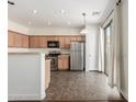 Well-lit kitchen featuring stainless steel appliances, light wood cabinets, and access to the patio at 25792 W Burgess Ln, Buckeye, AZ 85326