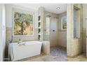 Bright bathroom featuring a modern tub, a glass shower with double shower heads, and scenic outdoor views at 27641 N 74Th St, Scottsdale, AZ 85266