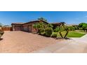 Exterior view of the home with a paver driveway, stone accents, and mature landscaping at 3464 E Dartmouth St, Mesa, AZ 85213