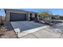 Long concrete driveway leading to a two-car garage with manicured landscaping and hardscape at 36243 W San Clemente Ave, Maricopa, AZ 85138