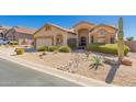 Charming single-story home with desert landscaping and a well-manicured lawn, complemented by a two-car garage at 7703 E Sayan St, Mesa, AZ 85207