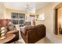 Spacious living room featuring plush brown sofas, a ceiling fan, and a passthrough to the kitchen at 14950 W Mountain View Blvd # 4103, Surprise, AZ 85374