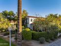 Exterior view of a charming home showcasing lush landscaping, a tile roof, and mature trees at 1614 Palmcroft Sw Dr, Phoenix, AZ 85007