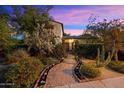 Inviting home exterior with lush landscaping, a brick path, and mature desert plants under a vibrant sky at 1614 Palmcroft Sw Dr, Phoenix, AZ 85007