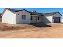 Charming single-story home featuring white stucco siding, dark trim and a gray garage door at 16560 N Slate Ln, Maricopa, AZ 85139