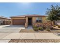 Charming single-story home with a well-manicured front yard, stone accents, and a two-car garage at 17577 W Desert Bloom St, Goodyear, AZ 85338