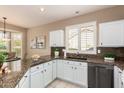 Bright kitchen with granite countertops, sleek black appliances, custom cabinets, and a large window overlooking the backyard at 21402 N 158Th Dr, Sun City West, AZ 85375