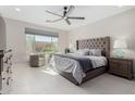 Spacious bedroom with tiled floors, a ceiling fan, a large window, and a luxurious upholstered bed at 25913 W Sands Dr, Buckeye, AZ 85396