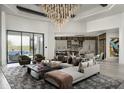 Bright, open living room with modern chandelier, neutral palette and expansive glass doors to the outdoor pool and lounge area at 37975 N 98Th Pl, Scottsdale, AZ 85262