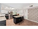 Bright kitchen featuring stainless steel appliances, a center island with bar stools, and skylight at 3927 W Phelps Rd, Phoenix, AZ 85053