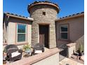 Exterior entrance featuring a stone turret, landscaped walkway, and comfortable seating at 42024 W Rosewood Ln, Maricopa, AZ 85138